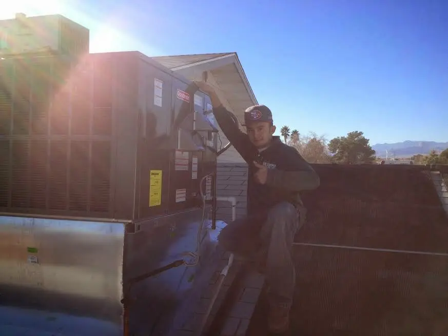 HVAC technician performing Air Duct Repair on a rooftop unit in Lancaster